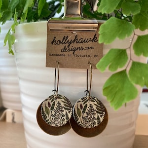 May include: A pair of brass earrings with a floral pattern on the front. The earrings are handmade in Victoria, BC by hollyhawkdesigns.com.