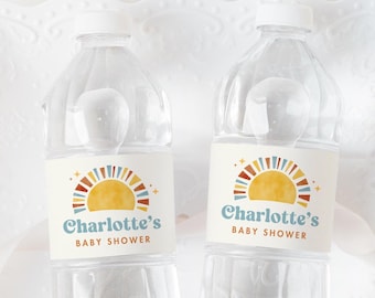 May include: Two clear plastic water bottles with labels that say "Charlotte's Baby Shower" and feature a colorful sun design. The bottles are on a white lace doily.