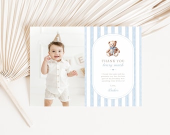 May include: A baby boy wearing a party hat and white shirt and shorts is featured on a thank you card. The card has a blue and white striped background with a teddy bear illustration and the text "Thank you berry much."