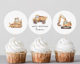 May include: Three cupcakes with white frosting and construction vehicle toppers. The toppers are round with watercolor illustrations of a bulldozer, dump truck, and excavator. The middle topper says "Happy Birthday Liam".