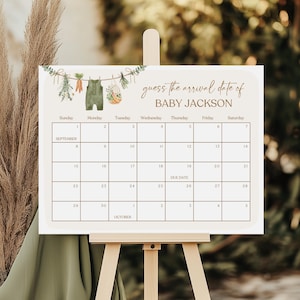 Puede incluir: Una tarjeta de juego de baby shower imprimible blanca con una ilustración de acuarela verde y marrón de un body de bebé colgado de una cuerda para tender la ropa con vegetación. El texto "guess the arrival date of BABY JACKSON" está en la parte superior de la tarjeta. Una cuadrícula de calendario con los meses de septiembre y octubre está debajo del texto. La fecha de vencimiento está marcada en el calendario.