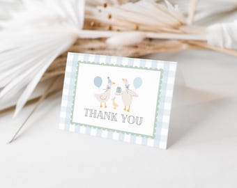 May include: A blue and white checkered thank you card with a green border. The card features a cartoon illustration of two ducks with blue balloons and a baby duck. The text "THANK YOU" is printed in black.