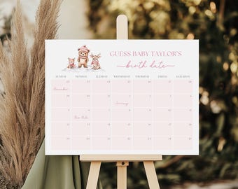 May include: A light pink calendar on an easel with the text "GUESS BABY TAYLOR'S birth date". The calendar features a winter-themed illustration of three animals. The calendar grid includes dates for December and January.