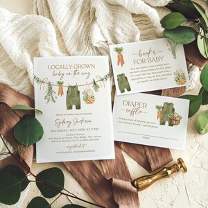 May include: A baby shower invitation with a green and brown color scheme. The invitation features a cartoon illustration of a baby's overalls hanging on a clothesline with carrots, herbs, and a basket of vegetables. The text reads "Locally Grown Baby on the Way" and includes the baby's name, date, time, and location. There are also two cards for guests to bring a book or diapers for the baby.