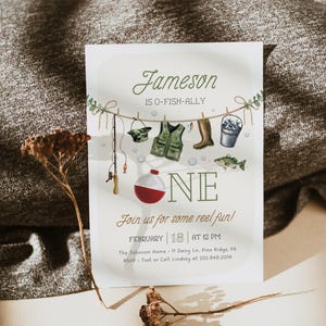 May include: A fishing-themed first birthday party invitation with a green and brown color scheme. The invitation features a watercolor illustration of fishing gear, including a fishing rod, a life vest, a bucket, and a fish. The text on the invitation reads "Jameson is O-Fish-Ally One" and includes the date and time of the party.