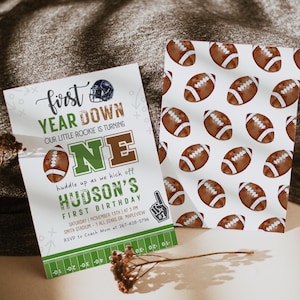 Puede incluir: Una invitaci&oacute;n a una fiesta de primer cumplea&ntilde;os con tem&aacute;tica de f&uacute;tbol americano, en colores verde y marr&oacute;n, con el texto "First Year Down Our Little Rookie is Turning One" y "Hudson's First Birthday".
