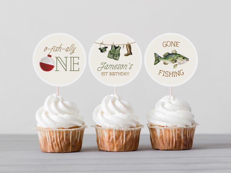 May include: Three white cupcakes with round, white toppers. The toppers have a fishing theme and say "o-fish-ally one", "Jameson's 1st Birthday", and "Gone Fishing".