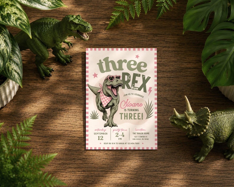 May include: A rectangular birthday invitation card with a pink and white checkered border. The card features a green T-Rex wearing pink heart-shaped sunglasses and a pink bandana, with the text "three REX" and "Sloane IS TURNING THREE!"