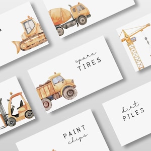 May include: Watercolor illustrations of construction vehicles and related items on white cards. The cards include images of a bulldozer, cement mixer, crane, forklift, dump truck, and excavator. Text on the cards reads: Wrecking balls, spare tires, metal beams, nuts & bolts, paint chips, and dirt piles.