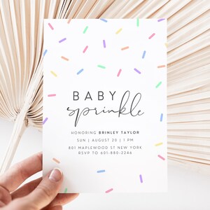 Puede incluir: Una invitaci&oacute;n de baby shower blanca con un patr&oacute;n de chispas de colores y el texto "BABY sprinkle" en escritura cursiva negra. La invitaci&oacute;n incluye el nombre "BRINLEY TAYLOR", la fecha "SUN AUGUST 20", la hora "1 PM", la direcci&oacute;n "801 MAPLEWOOD ST NEW YORK" y la informaci&oacute;n de RSVP "RSVP TO 601-880-2246".