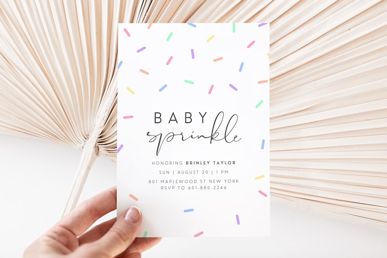 Puede incluir: Una invitaci&oacute;n de baby shower blanca con un patr&oacute;n de chispas de colores y el texto "BABY sprinkle" en escritura cursiva negra. La invitaci&oacute;n incluye el nombre "BRINLEY TAYLOR", la fecha "SUN AUGUST 20", la hora "1 PM", la direcci&oacute;n "801 MAPLEWOOD ST NEW YORK" y la informaci&oacute;n de RSVP "RSVP TO 601-880-2246".