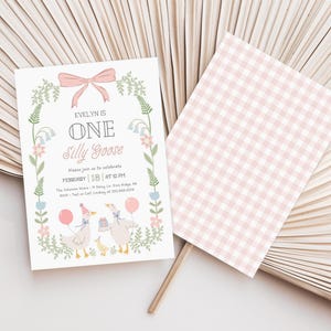 Puede incluir: Una invitaci&oacute;n con estampado de cuadros vichy rosa y blanco con un borde floral y dos gansos de dibujos animados. El texto dice "Evelyn is One Silly Goose" e incluye la fecha y la hora del evento.