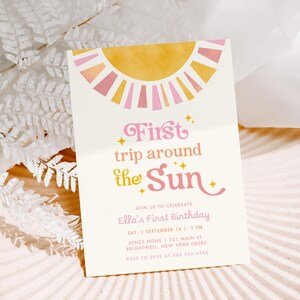 May include: A cream-colored invitation with a sun design in yellow and pink. The text reads "First trip around the Sun" in pink script. Additional text includes birthday details and RSVP information.