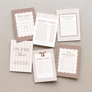 May include: A selection of baby shower game cards in brown and white. Games include Baby Bingo, Mommy or Daddy, Baby Name Race, Pacifier Hunt, Wishes for Baby, and Baby Predictions. The cards have decorative borders and text, perfect for a baby shower.