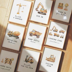 Puede incluir: Una colección de impresiones en acuarela enmarcadas con ilustraciones de temática de construcción. Cada impresión presenta un vehículo o elemento de construcción diferente, como una grúa, una excavadora o un camión volquete, con texto lúdico como "Build a Burger" y "Loading Zone."