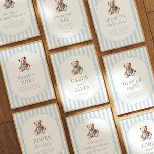 Puede incluir: Un conjunto de letreros para baby shower con temática de osito de peluche. Cada letrero presenta una ilustración de osito de peluche en acuarela y texto como "Tarjetas y regalos", "Rifa de pañales" y "Libros para bebés". Los letreros tienen un fondo a rayas azules y blancas.