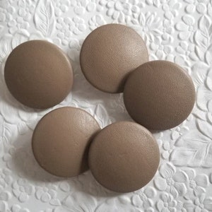 May include: Five brown round buttons with a textured surface.