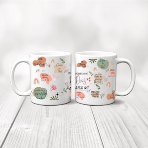 May include: Two white ceramic mugs with handles. The mugs are decorated with colorful illustrations and text in Spanish. The text on the mugs includes phrases like "Dios es amor" and "Promesas de Dios para mi".