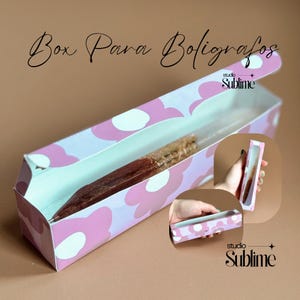 Puede incluir: Caja rectangular para bolígrafos con un estampado floral rosa y el texto "Box Para Bolígrafos". La caja está abierta, revelando un bolígrafo en su interior. La caja también tiene el texto "studio Sublime".