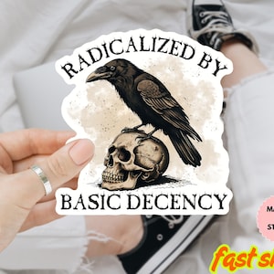 Puede incluir: Adhesivo con un cuervo negro posado sobre una calavera humana. El texto "RADICALIZED BY BASIC DECENCY" está arqueado arriba y abajo de la imagen. Resistente al agua, se puede usar como imán.