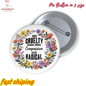 Op de afbeelding: Een witte speldknop met de tekst "WHEN CRUELTY BECOMES NORMAL Compassion SEEMS RADICAL" omringd door een bloemenkrans. De knop is verkrijgbaar in 3 maten. De speld heeft een zilveren achterkant.