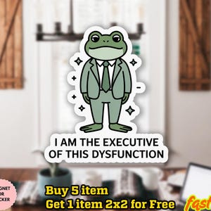 May include: A sticker featuring a cartoon frog in a suit with the text "I AM THE EXECUTIVE OF THIS DYSFUNCTION." The frog is green with a white outline. The sticker is water-proof and can be used as a magnet.