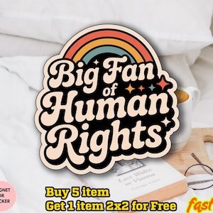 May include: A sticker or magnet with the text "Big Fan of Human Rights" in a retro font, featuring a rainbow and stars. The design is black, beige, orange, yellow, and blue. The image also includes a book, glasses, and a mug.