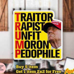 Może przedstawiać: Żółta naklejka z czarnym i czerwonym tekstem z napisem "TRAITOR RAPIST UNFIT MORON PEDOPHILE" ze zdjęciem mężczyzny w czerwonej czapce. Naklejka znajduje się na drewnianym stole.