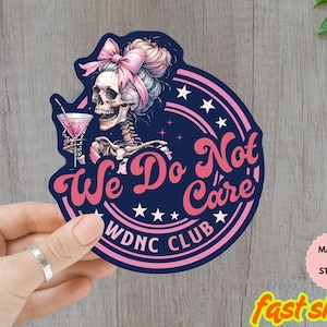 Puede incluir: Adhesivo azul marino con un esqueleto con un lazo rosa, sosteniendo un cóctel. El adhesivo tiene el texto "We Do Not Care" y "WDNC CLUB" en rosa y blanco. El adhesivo es resistente al agua.