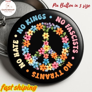 May include: Black pinback button with a floral peace sign design. The button has the phrases "NO KINGS", "NO FASCISTS", "NO TYRANTS", and "NO HATE" in various colors. The text "Pin Button in 3 size" is also visible.
