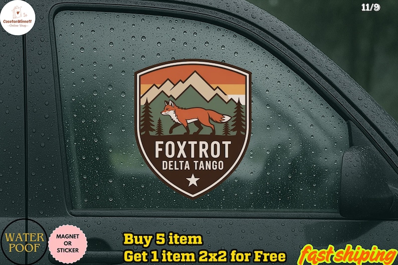 May include: A shield-shaped sticker featuring a fox walking in front of a mountain range and pine trees. The sticker has the text "FOXTROT DELTA TANGO" and a star at the bottom. The sticker is brown, orange, and green.