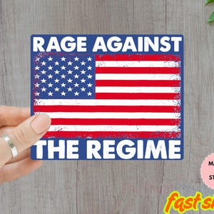May include: A rectangular magnet or sticker with a distressed American flag design. The text "RAGE AGAINST THE REGIME" is displayed in white, bold letters. The item is held by a person. The item is water-resistant.