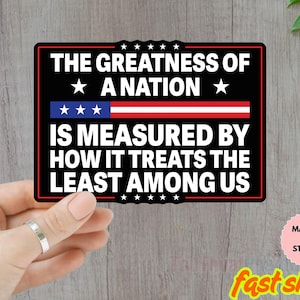 May include: Black rectangular magnet or sticker with the text "THE GREATNESS OF A NATION IS MEASURED BY HOW IT TREATS THE LEAST AMONG US." The design includes stars and a red, white, and blue stripe.