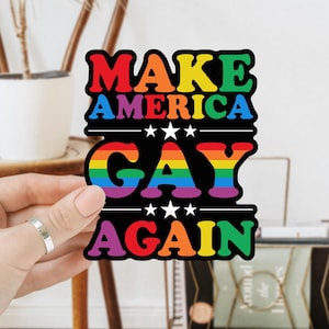 May include: A sticker with the text "Make America Gay Again" in rainbow colors. The text is in a bold, retro font.