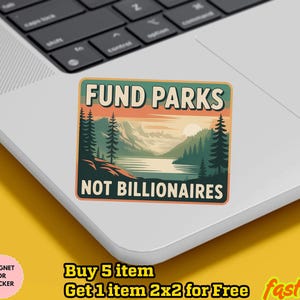 May include: A rectangular sticker with the text "FUND PARKS NOT BILLIONAIRES" in a landscape design. The design features a lake, mountains, and trees in shades of green, orange, and blue. The sticker is on a laptop.