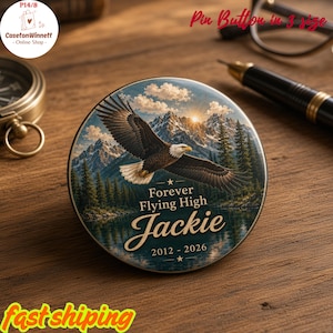 May include: A round pin button featuring a bald eagle in flight over a mountain lake landscape. The text reads Forever Flying High, the name Jackie, and the years 2012 - 2026. The design includes a sunrise, pine trees, and snowy peaks.