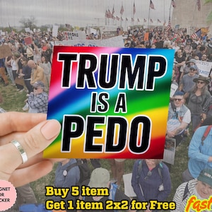 Może przedstawiać: Kolorowa naklejka z napisem "TRUMP IS A PEDO" w pogrubionym czarnym kolorze na tęczowym tle. Naklejka jest trzymana przed tłumem ludzi podczas protestu.
