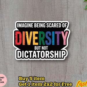 Op de afbeelding: Een sticker met de tekst "IMAGINE BEING SCARED OF DIVERSITY BUT NOT DICTATORSHIP" in regenboogkleuren. De sticker is zwart met een witte rand en staat op een houten ondergrond. De sticker is een magneet of sticker.
