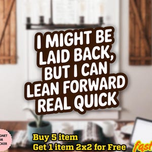 以下が含まれることがあります： 「I MIGHT BE LAID BACK, BUT I CAN LEAN FORWARD REAL QUICK」と書かれた白い文字の茶色のステッカー。ステッカーは、テーブルとラップトップのある部屋のぼやけた背景の前にあります。