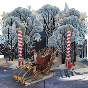 Kringledom! 3D Pop-Up Holiday Gift Card przedstawiająca Świętego Mikołaja jadącego na sankach przez zimową krainę czarów na Biegunie Północnym