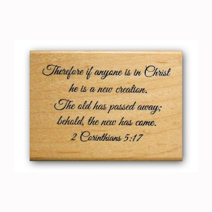 May include: A wooden stamp with the text "Therefore if anyone is in Christ he is a new creation. The old has passed away; behold, the new has come. 2 Corinthians 5:17"
