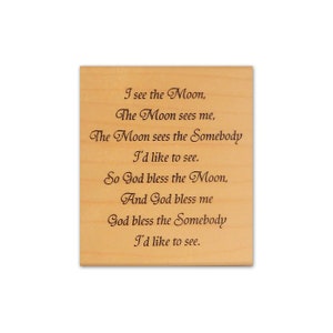 Könnte beinhalten: Eine hellfarbene Holztafel mit dem eingravierten Text eines Gedichts. Das Gedicht beginnt mit "I see the Moon" und fährt mit mehreren Zeilen über den Mond und Segnungen fort. Der Text ist dunkelbraun.