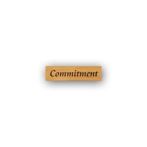 May include: Wooden stamp with the word "Commitment" engraved in black ink.