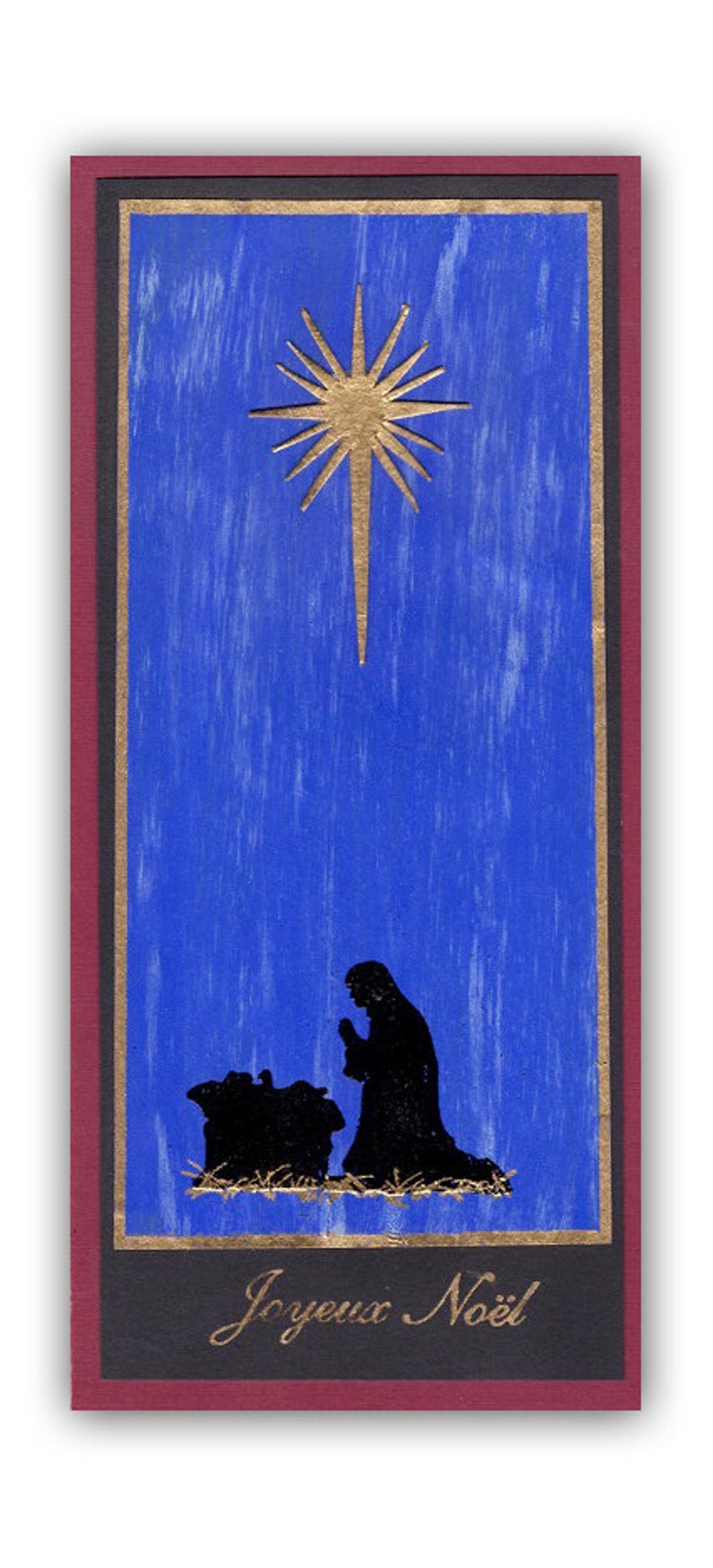 Op de afbeelding: Een blauwe en gouden kerstkaart met een ster en een silhouet van de kerststal. De kaart heeft de tekst "Joyeux No&euml;l".
