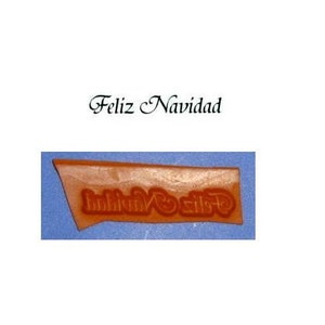 May include: A brown rubber stamp with the words "Feliz Navidad" in a decorative font.