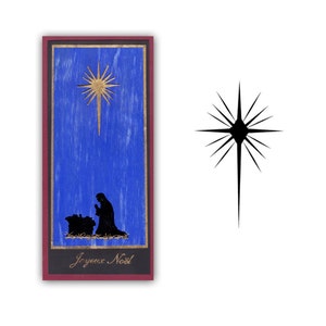 May include: A blue wooden sign with a gold star and a silhouette of a person kneeling before a manger. The sign says "Joyeux Noel" in gold lettering.
