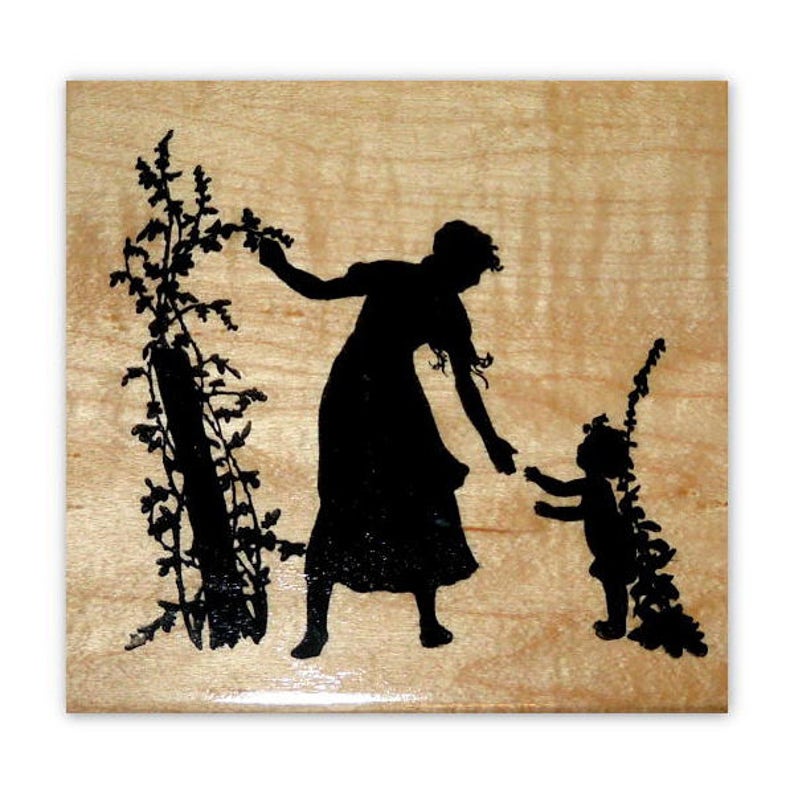 May include: A black silhouette of a mother and child standing in a field of flowers. The mother is holding a flower in her hand and the child is looking up at her.