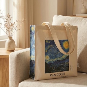May include: A beige canvas tote bag featuring Van Gogh's "Starry Night" painting. The bag has a rectangular shape with a matching beige handle. The artwork is printed on the front, with the artist's name and the painting's title at the bottom.