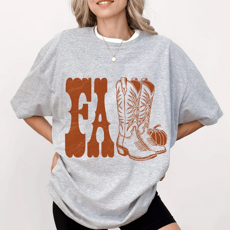 May include: A light gray sweatshirt with a brown graphic that says "FA" and features a pair of cowboy boots and a pumpkin. The boots have intricate floral designs.