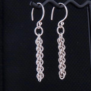 May include: A pair of silver chain earrings with a simple hook closure. The earrings are approximately 2 inches long.